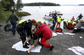 Zraněná žena na břehu naproti ostrovu Utøya (v dálce) poté, co byla zachráněna před Breivikem, který na ostrově 22. července 2011 povraždil  členy mládežnického křídla vládnoucí strany práce, kteří tam byli na táboře. (Foto: profimedia.cz)