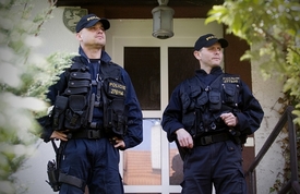 Policie střeží vchod do domu v Hostivicích.
