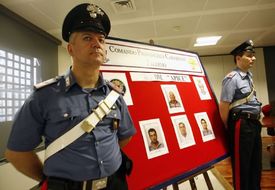 Policisté stojí u snímků podezřelých mafiánů.