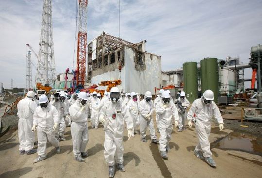 Japonští reportéři v maskách u havarované jaderné elektrárny Fukušima.