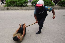 Policista bije protestující textilní dělnici.