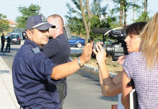 Policista decentně brání kameramance v práci.