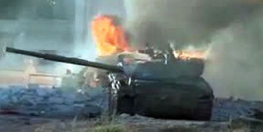 Hořící tank vladního vojska zasažený rebely. 