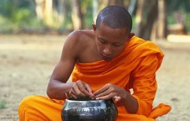 Thajský mnich při jídle.