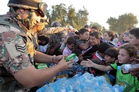 Jordánští vojáci rozdávají vodu nově příchozím běžencům.