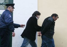 Řecká policie eskortuje zadrženého muže. 