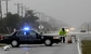 Policista staví zátaras na silnici v Nags Head ve státě Severní Karolína, kde hurikán způsobil zaplavení silnice. 