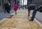 Pracovník údržby upevňuje překližky na chodníkové rošty budovami na Broadwayi v New Yorku. 