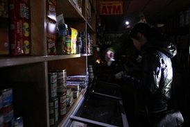 V obchodech se vše odehrává potmě, lidé si při výběru potravin svítí baterkami. New York bude bez elektřiny ještě několik dní.
