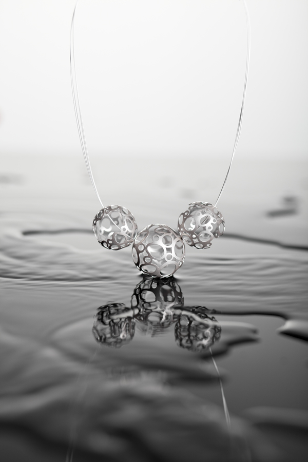 Stříbrný náhrdelník Holeganic Aleny Hesounové kombinuje precizní kulové tvary, jejichž povrch je však narušován mnohými otvory. 
