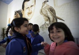 Syrské školačky pod obrázkem Asada se sokolem (říjen 2012). 