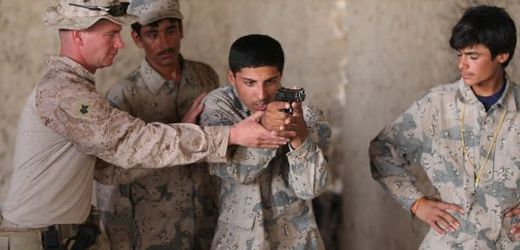Americký mariňák učí afghánské vojáky střílet s pistolí.