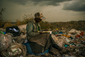 Nairobi, Kenya, skládka Dandora. Americký fotograf Micah Albert zachytil při pauze ženu, který pracuje jako sběračka odpadků na 30akrové skládce, kde se nachází odpad milionu lidí žijících v okolních slumech. Žena si občas najde chvilku, aby prolistovala vyhozené knihy a časopisy. "Dává mi to něco nového, jiného než jen sbírání odpadků," říká.