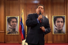 Hugo Chávez na snímku z Caracasu. V pozadá vidíme portréty Simona Bolívara.