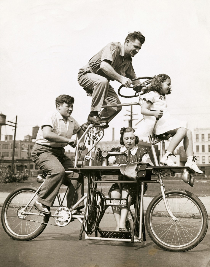 Trochu bláznivý, ale důmyslně sestavený kvadrocykl. Rodina Charlese Steinlaufa na jím sestaveném kole, které pohání šicí stroj. Vlevo syn Fred, vpředu dcera Ruth a manželka vynálezce u stroje, který kolo pohání. 