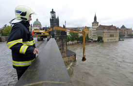 Bagr odklízí naplaveniny na uzavřeném Karlově mostě v Praze.