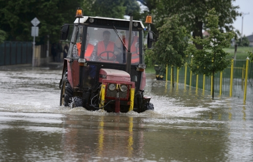 Traktor v Hoříně u Mělníka projíždí vodou, která 4. června překonala protipovodňovou hráz a zaplavila obec i její místní části. 