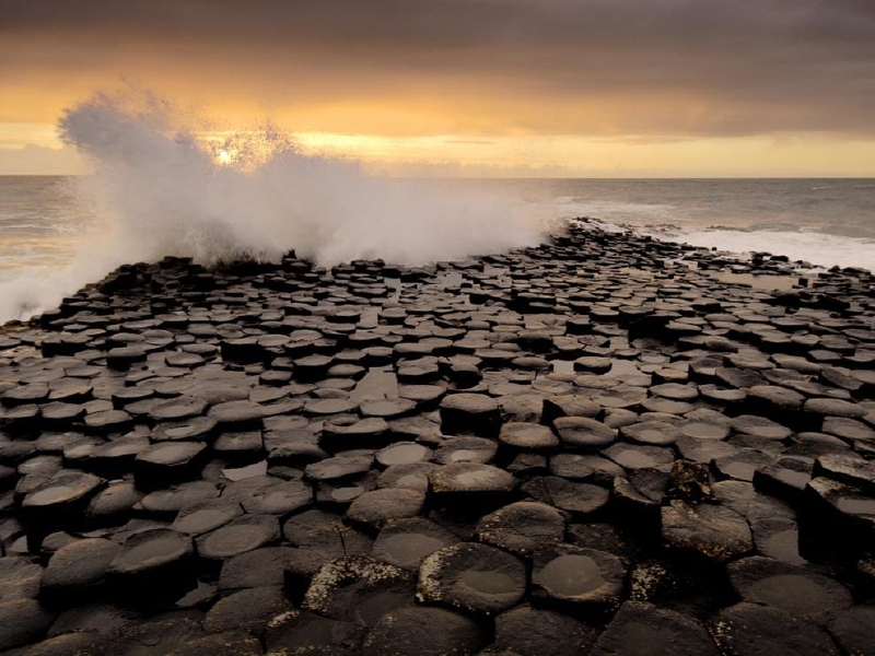 Obří hráz, Severní Irsko. Pláž tvoří víc než 38 tisíc čedičových sloupů, které připomínají chodník mizící v moři. Za jejich vznikem stojí sopečná erupce. (Foto: Science.nationalgeographic.com)
