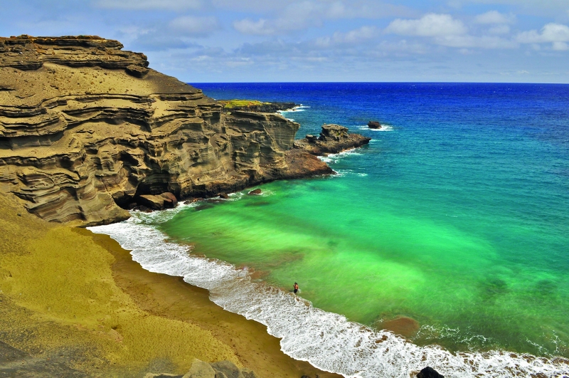 Pláž Papakolea, Havaj. Zelenou barvu pobřeží dává minerál olivín, který vzinká sopečnou aktivitou. Olivín je první krystalickou formou ztuhlého magmatu. (Foto: Westhawaiitoday.com)
