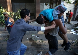 Kamarádi odnášejí mladíka, přívržence vojenského režimu, zraněného po střetu s fanoušky svrženého prezidenta Mursího.