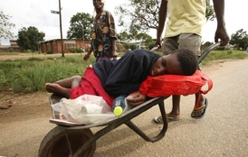 Muž převáží ženu nemocnou cholerou do nemocnice v Harare (2008).