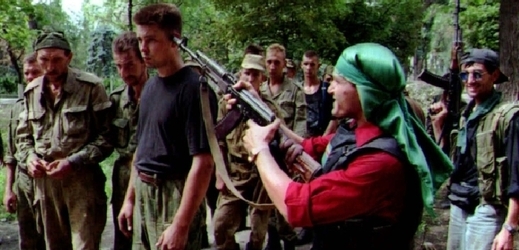 Čečenští rebelové míří zbraní na hlavu zajatého ruského vojáka.