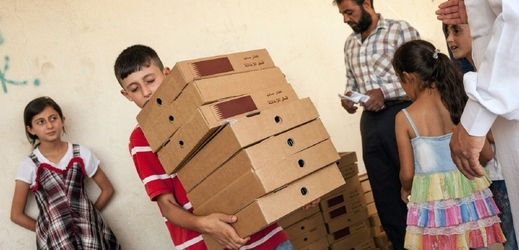 Chlapec nese zásoby jídla v jednom z uprichlických táborů v Sýrii.