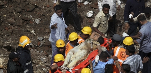 Indičtí záchranáři vynáší přeživší z trosek budovy.