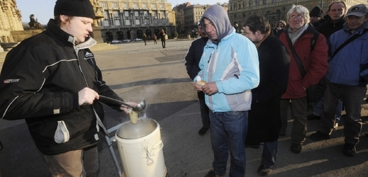 Pracovníci charitativní společnosti Naděje rozlévají na Alšově nábřeží v Praze lidem bez přístřeší polévku a teplý čaj.
