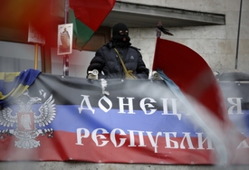 Maskovaný pro-ruský aktivista na balkónu budovy regionální správy s vlajkou s nápisem "Doněcká republika". Doněck, Ukrajina.