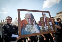 Studenti teologie z Říma s obrázky svatořečených. Turisté se s nimu můžou vyfotit.