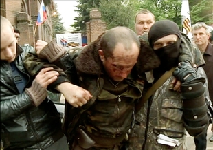 Sestřeleného a zraněného pilota ukrajinského vrtulníku podpírají domobranci.