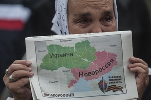 Babička z Doněcku drží noviny s mapou rozdělené Ukrajiny. V pravo dole historické Novorusko.