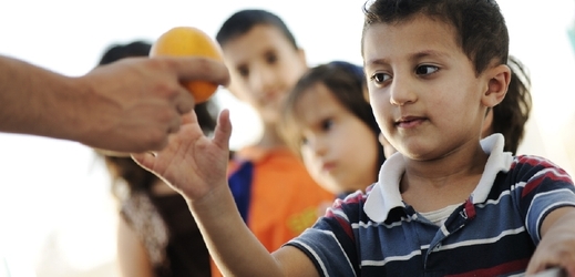 Děti v uprchlickém táboře dostávají příděly ovoce.  