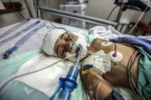 Těžce zraněný palestinský chlapec po dopadu izraelské bomby.