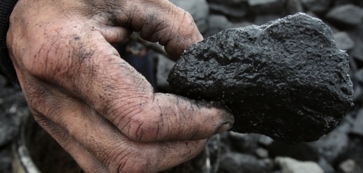 Jeden z haldařů drží v ruce kus černého uhlí.