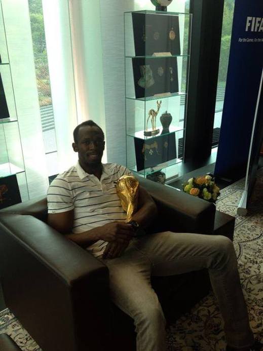 Usain Bolt se pomazlil s pohárem pro vítěze fotbalového mistrovství světa.