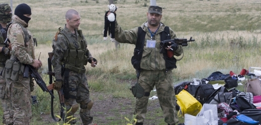 Proruský separatista drží hračku nalezenou mezi sutinami letadla u vesnice Hrabové. Pátek, 18. 7. 2014.