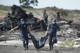 Ukrajinští záchranáři odnášejí v igelitových pytlích těla obětí z místa havárie.