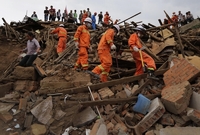 Záchranáři prochází troskami domů, které byly zničeny zemětřesením.