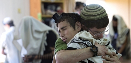Izraelští studenti se objímají před modlitbou v synagoze, kde dva z unesených mladíků studovali.