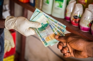Hygienická opatření v Sieře Leone. Prodaveč bere peníze v rukavicích.