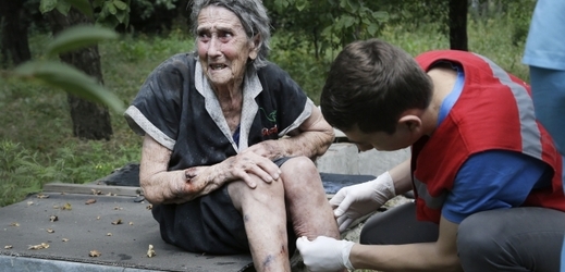 Zdravotník ošetřuje zraněnou ukrajinskou seniorku.