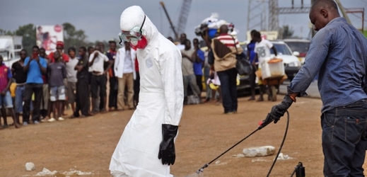 Zdravotní pracovník je sprejován dezinfekčním prostředkem jako prevencí proti ebole.