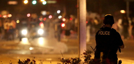 Policista sleduje situaci po použití slzného plynu proti demonstrantům v americkém městě Ferguson.