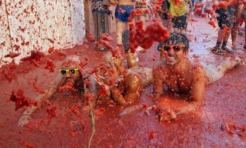 Nadšení účastníci rajčatové bitvy se do boje vrhají po hlavě.