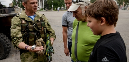 Separatista v centru Doněcku ukazuje svou výzbroj včetně granátu.
