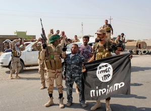 Šíitští bojovníci v Iráku s ukořistěnou vlajkou IS.