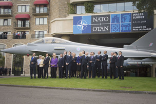 Účastníci summitu NATO před maketou vojenského letounu.