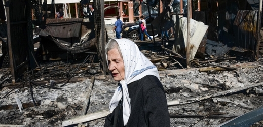 Žena prochází kolem trosek obchodu zničeného po odstřelování v Doněcku.